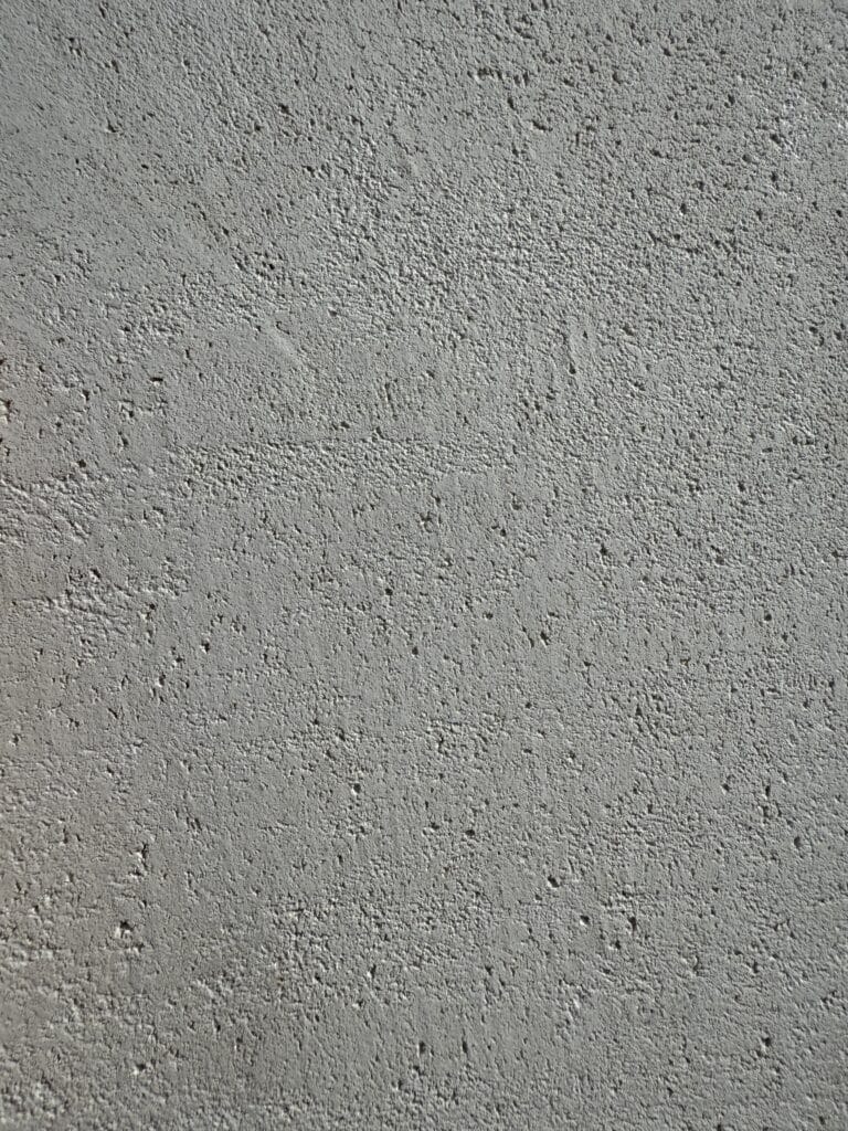 Texture rugueuse d'un mur en béton gris clair. Surface granuleuse et irrégulière, idéale pour fond ou arrière-plan industriel.