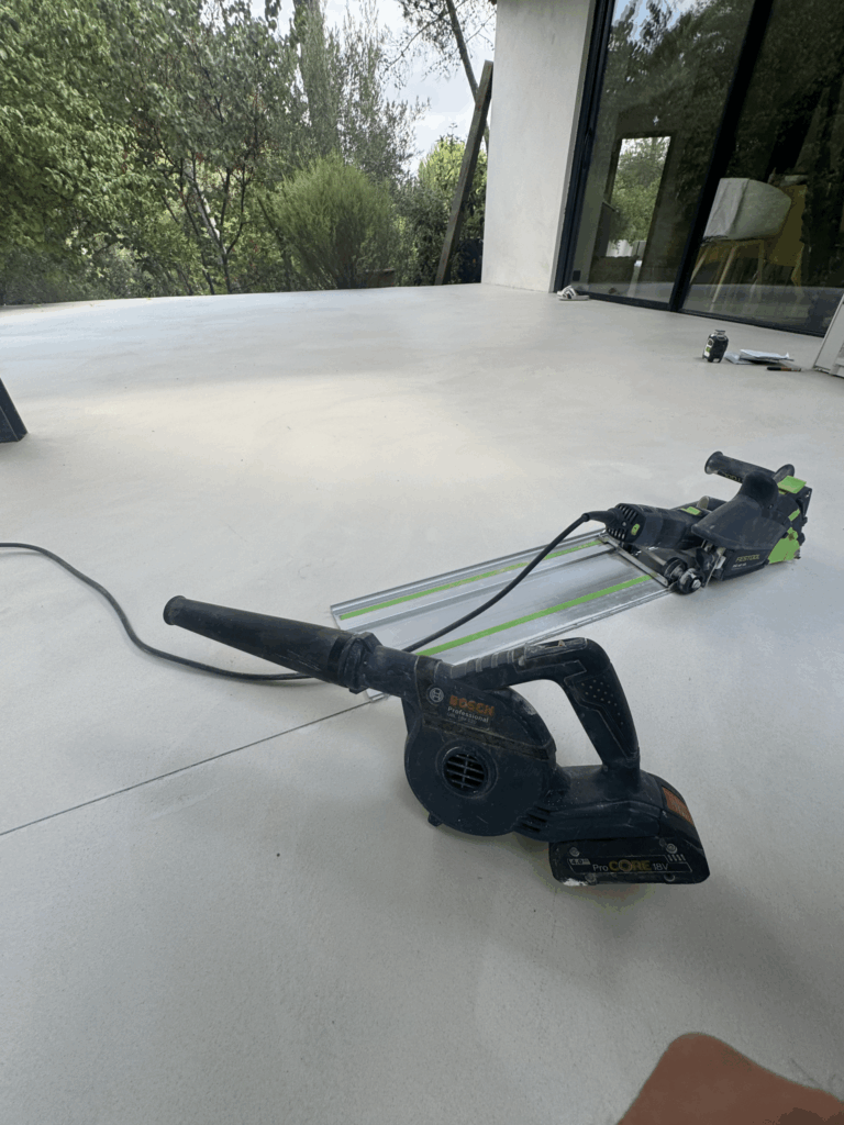 Souffleur Bosch GBL 18V-120 et scie Festool sur rail sur une terrasse en béton en plein air.